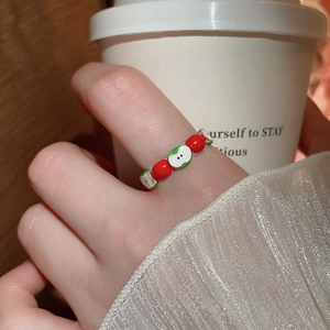 Close-up of a cute apple-shaped enamel ring with red beads worn on a finger