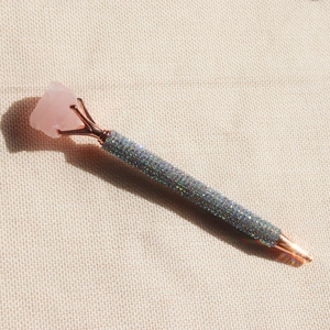 Detail of rose gold metal pen with shimmering sequins and raw pink crystal top