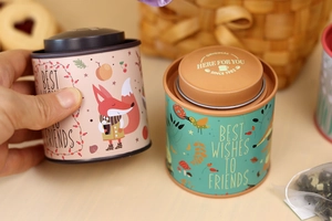 Close-up of pink and teal tin boxes featuring floral illustrations and greeting text