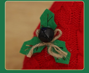 Close-up of knit Christmas gnome hat with green felt holly leaves and a black bell detail