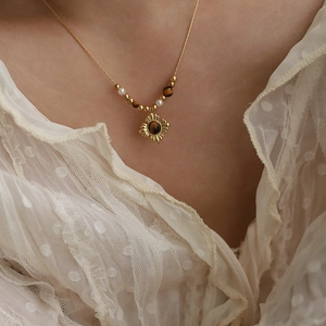 Model wearing gold tiger eye beaded necklace with sunburst pendant and pearls