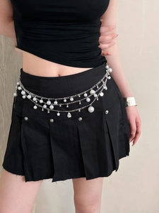 Detail of silver layered waist chain featuring pearls, stars and shell pendants on model