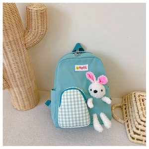 Detail of mint green kids backpack with checkered pocket and white plush bunny pendant