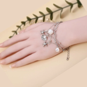 Detail of silver layered bracelet with starfish and shell charms worn on wrist