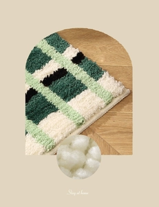 Détail du tapis pelucheux à carreaux verts montrant la texture douce des fibres blanches