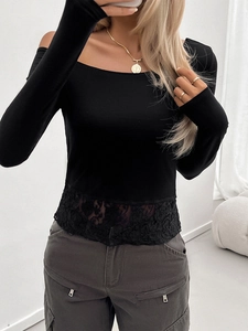 Detail of a slim fit black long sleeve top featuring delicate lace trim at the hemline