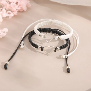 Close-up of black and white braided heart bracelets for couples with silver charms