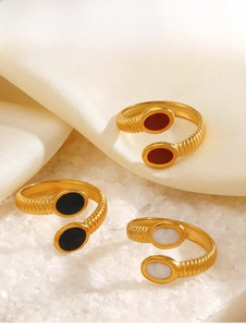 Detailed view of gold oval rings with red, black, and marble white enamel inlays