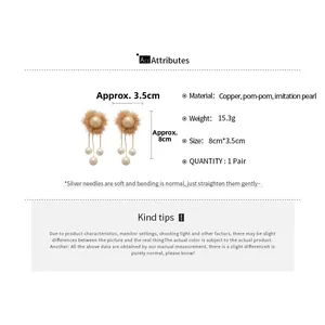 Detailed view of pom-pom drop earrings with imitation pearls and copper tassel