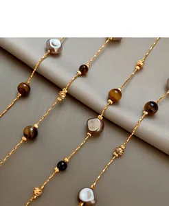 Détails macro de perles œil de tigre et perles grises sur une chaîne dorée à l'or 18 carats