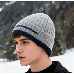 Detail of grey winter knit beanie with blue stripes against a snowy mountain backdrop
