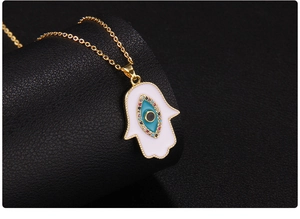 Macro detail of Hamsa Hand pendant with Evil Eye in white enamel on black leather background