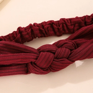 Close-up of red ribbed knitted headband featuring a stylish central knot design