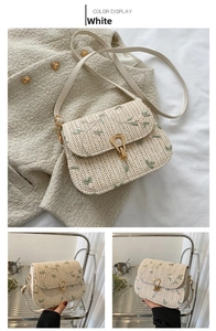 Close-up of floral embroidery and golden metal clasp on a woven straw crossbody bag
