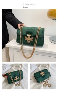 Detail of green snake pattern crossbody bag with ornate bee buckle and gold chain strap