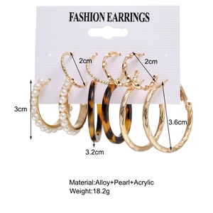Detail view of gold alloy hoop earrings with pearls and amber acrylic on a display card