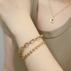 Détail de bracelets double couche en émail kaki et perles dorées sur le poignet