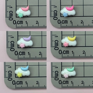 Close-up of cloud-shaped resin accessories with star and moon charms on a scale mat
