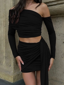 Elegant black two-piece set featuring off-shoulder long sleeve top and ruched mini skirt