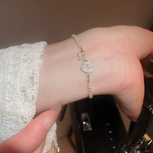 Detailed view of a gold-tone charm bracelet with zircon heart and star pendants on wrist
