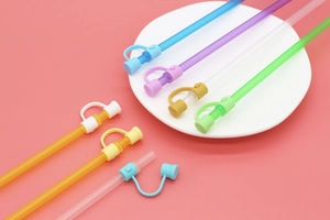 Close-up of colorful reusable silicone straw covers set on a pink background