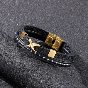 Macro detail of multi-layer black leather bracelet with stainless steel cross clasp