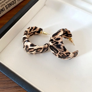 Close-up of leopard print C-hoop earrings with gold-toned metal in a jewelry box