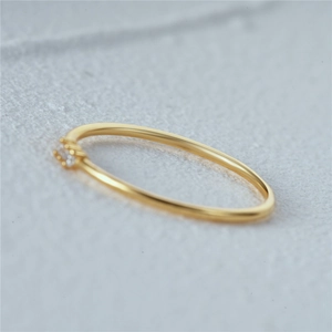 Macro shot of gold ring band featuring three sparkling gemstones on a grey surface