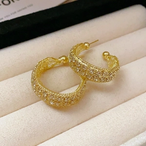 Detailed view of hollow mesh gold geometric earrings on a beige velvet jewelry display