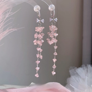 Détail de boucles d'oreilles pampilles en cristal rose avec nœud strass et perles gouttes