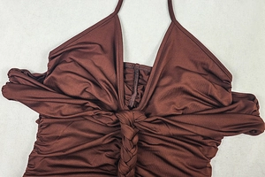 Detail of deep brown halter dress featuring twisted weave ornament and ruched fabric