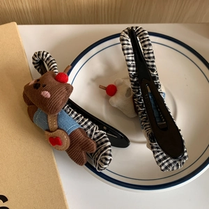 Detail of embroidered bear and black-white checkered fabric hair clips on a porcelain plate