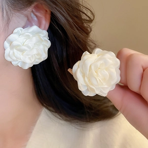 Close-up of elegant white fabric flower earrings with pearls on a model's ear