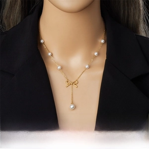 Detail of gold Y-necklace with pearls and bow pendant on a female model neck