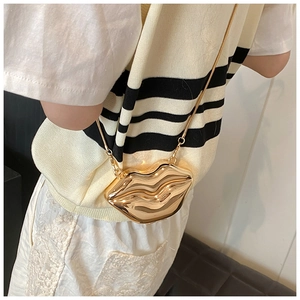 Detail view of mini gold lip-shaped metallic crossbody bag with sleek snake chain strap