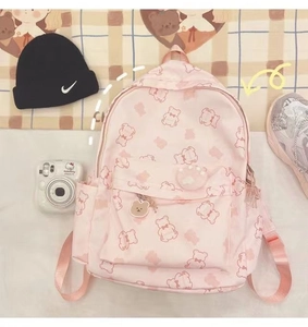 Detailed view of pink school backpack with bear prints and cute decorative pendants