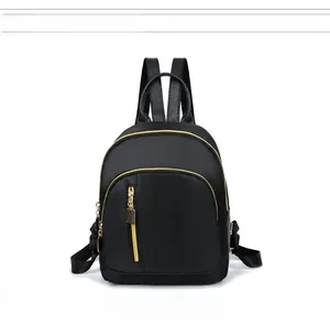 Front detail of black waterproof nylon backpack with golden zippers and leather handles