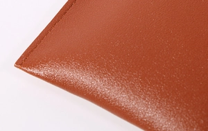 Detailed close-up of brown leather texture and precision stitching on the mini phone bag