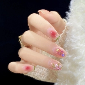Detail of handmade press-on nails featuring floral art and pink gradient glitters