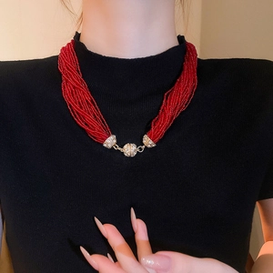Close-up of multilayer red bead necklace with sparkling rhinestone paved metal spheres