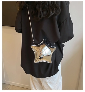 Star-shaped silver crossbody bag with metallic chain strap worn by a model