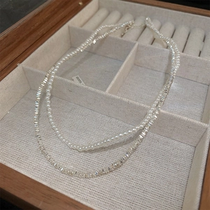 Detailed close-up of double-layer necklace with white pearls and faceted metallic beads