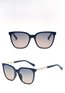 Detail view of square navy sunglasses featuring golden wave temples and pearl accents