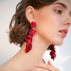 Élégantes boucles d'oreilles longues pétales de rose rouges portées par un mannequin