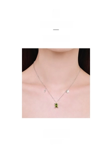 Detail of S925 silver necklace with emerald cut green stone and star charms on neck