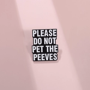 Detailed view of enamel pin with 'PLEASE DO NOT PET THE PEEVES' text on metal