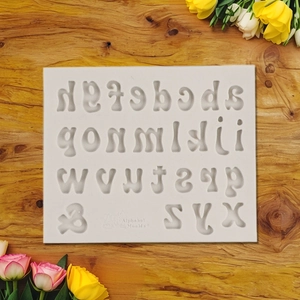 Close-up of white silicone alphabet mold with 26 letters and symbol for fondant and clay