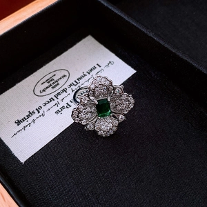 Macro detail of a vintage flower ring featuring a square emerald and zircon petals