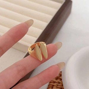 Detail of a minimalist gold teardrop open ring worn on a finger with a polished finish