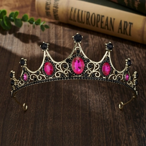 Close-up of vintage golden crown with magenta and black rhinestones on a wooden desk